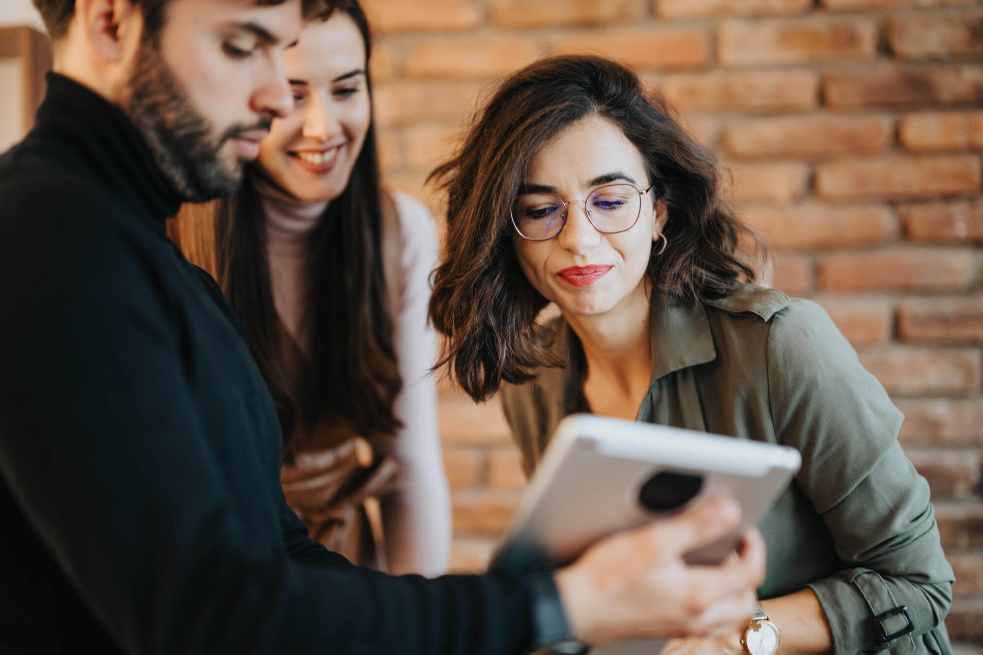 Engaged colleagues reviewing content on tablet in modern office