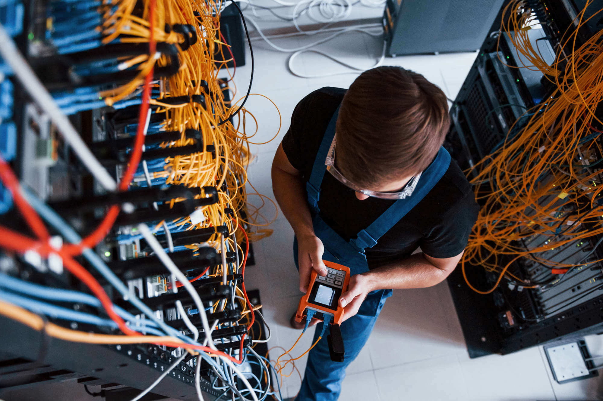 Top view of young man in uniform with measuring device that works with internet equipment and wires