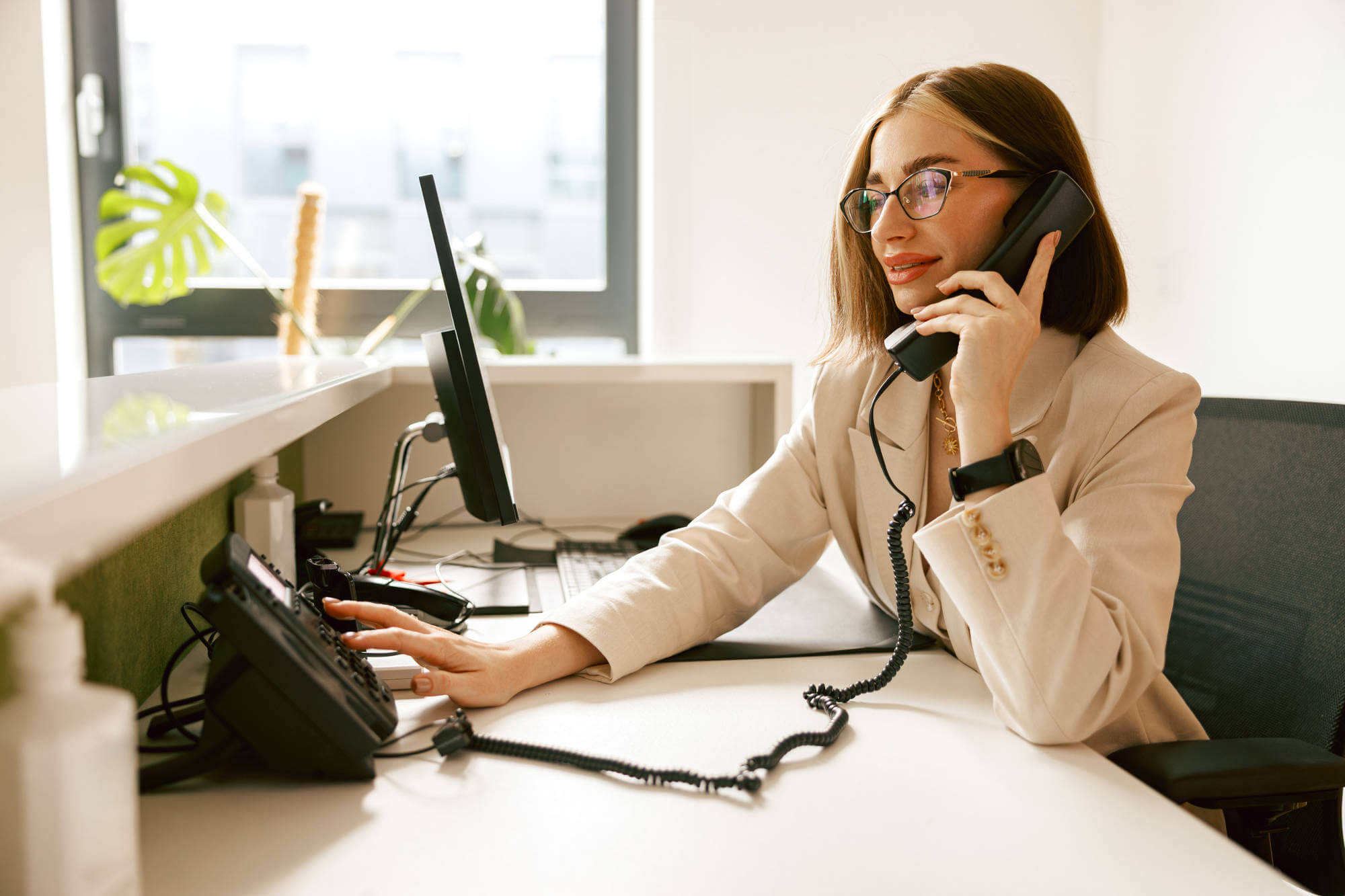 A dedicated professional businesswoman actively engaging with both her phone and computer at work