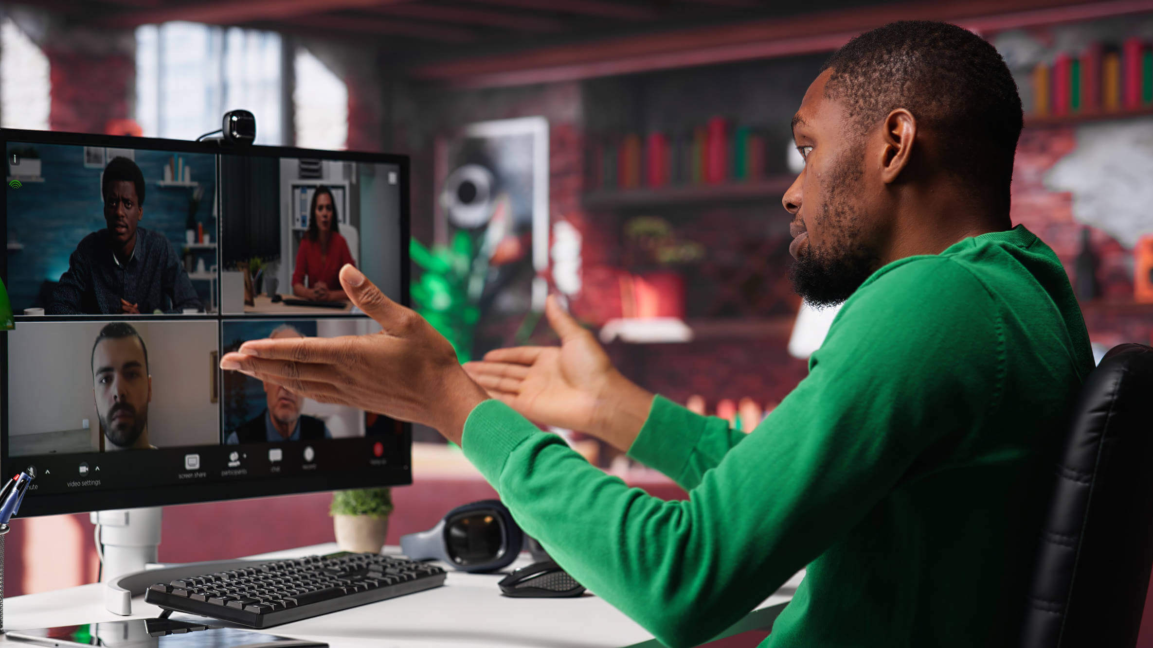 Remote worker looking at PC monitor discussing with coworkers during video call from home computer