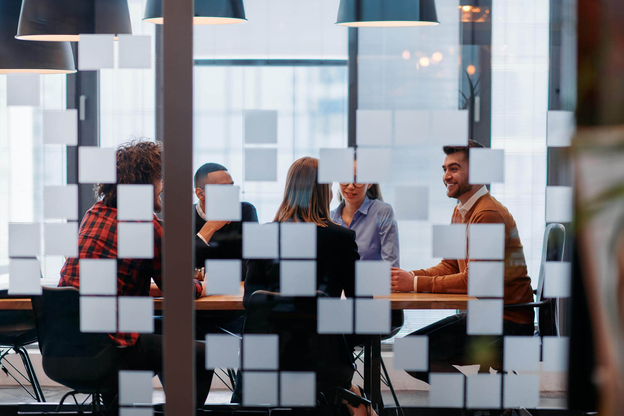 In a sleek glass office space, a team of business professionals engage in lively discussions and exchange strategic ideas